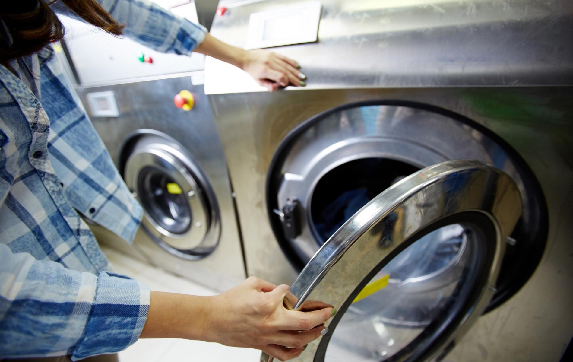 Chargement d'un lave-linge professionnel dans une buanderie