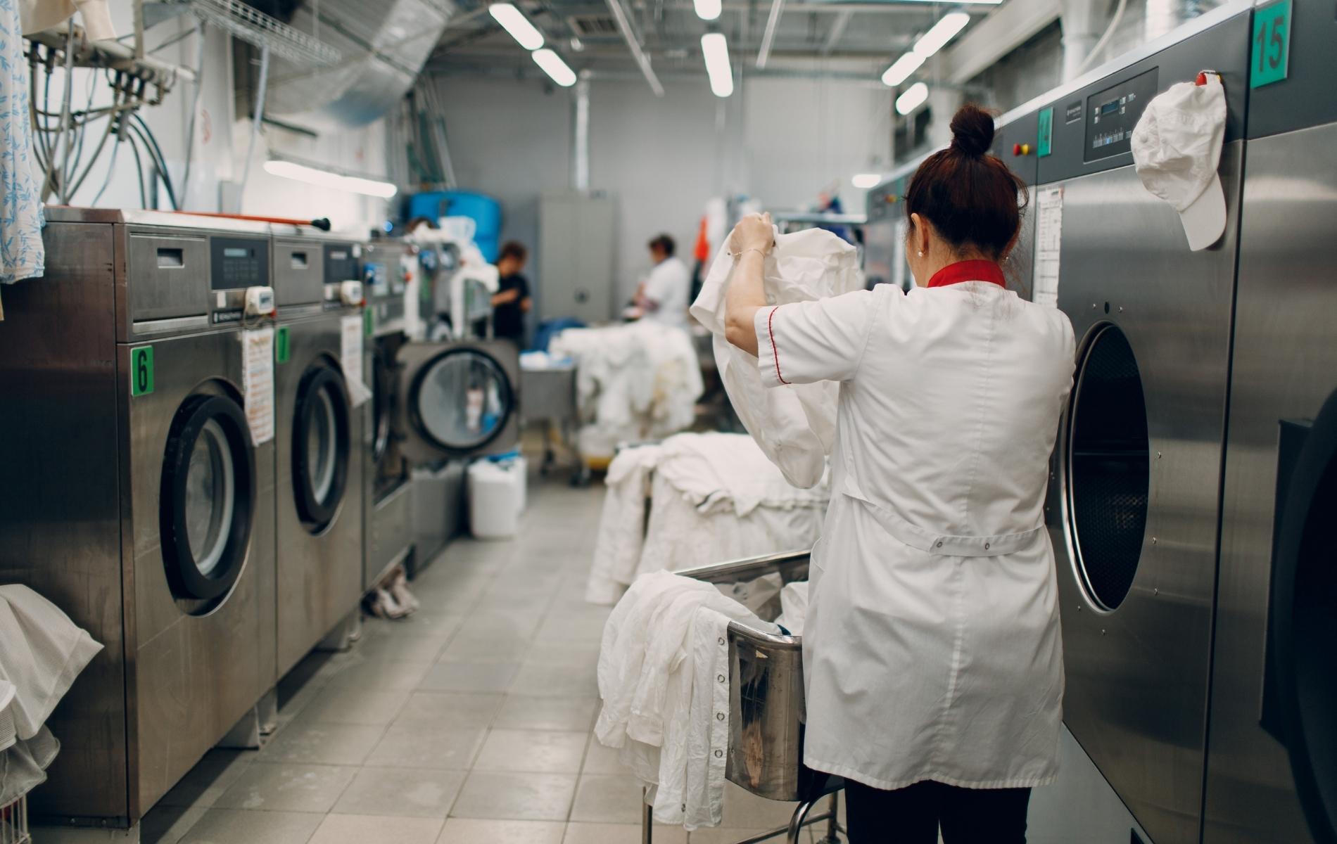 Buanderie professionnelle en activité avec lave-linge et personnel d'établissement