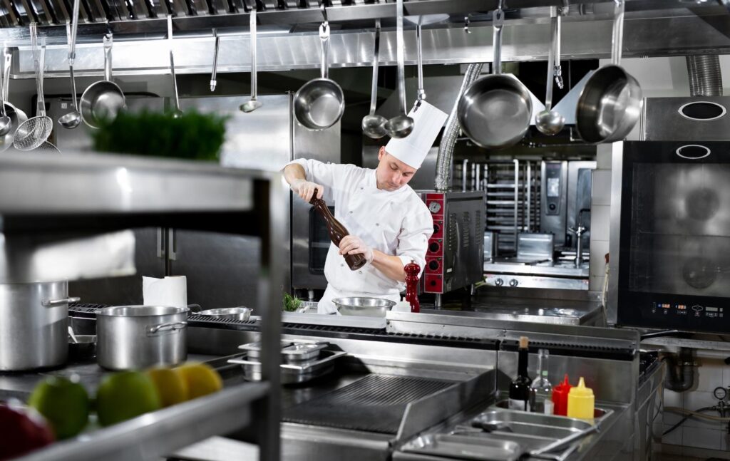 Cuisinier devant un four mixte dans une cuisine professionnelle équipée